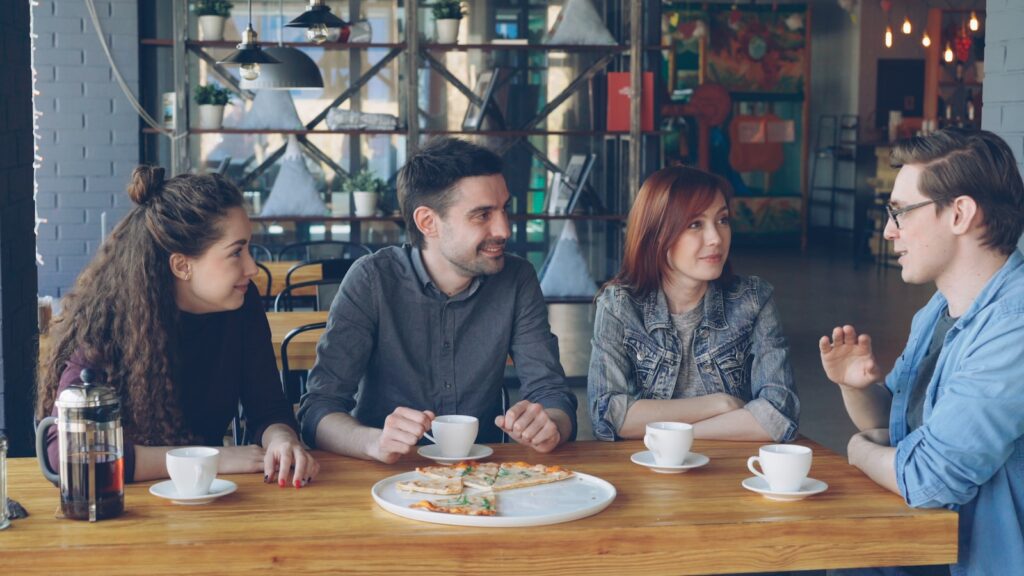 Friends chat and enjoy coffee at a cafe.