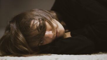 woman in black long sleeved shirt lying on white textile