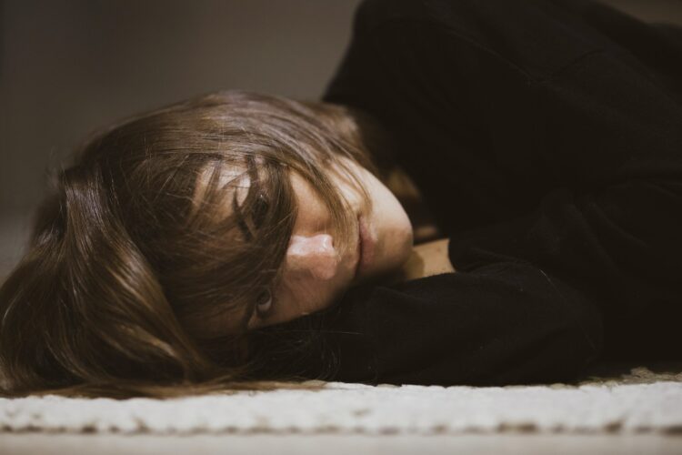 woman in black long sleeved shirt lying on white textile