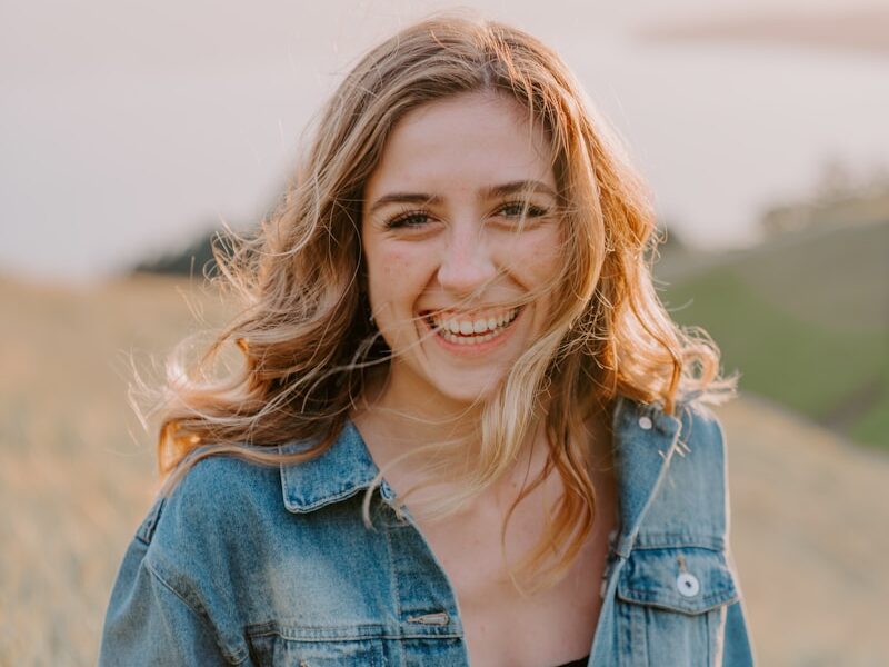 smiling woman sitting on grass during daytime