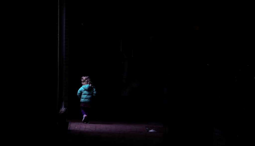 girl in teal long sleeve shirt and pink pants standing on brown wooden floor