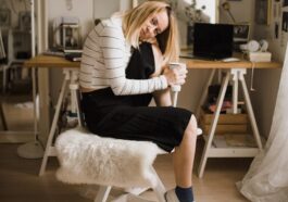 woman sitting on stool resting her head on her knee inside room