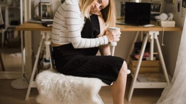 woman sitting on stool resting her head on her knee inside room