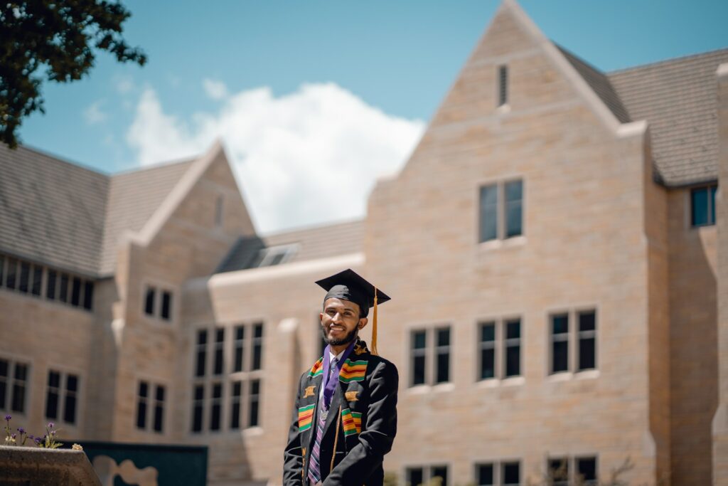 a man in a graduation gown standing in front of a building