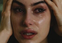 A woman crying with hands on her head.