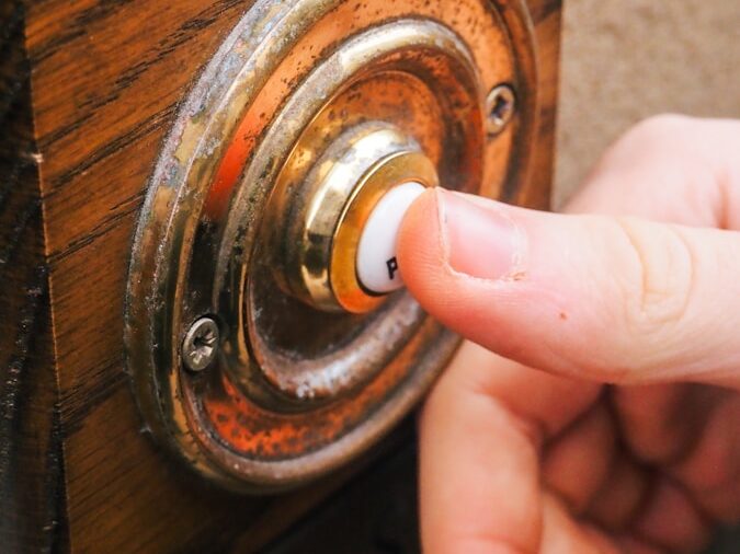 a person pressing a button on a wooden door
