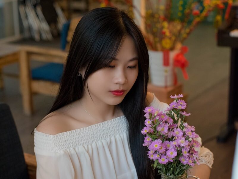 a woman sitting at a table holding a bouquet of flowers