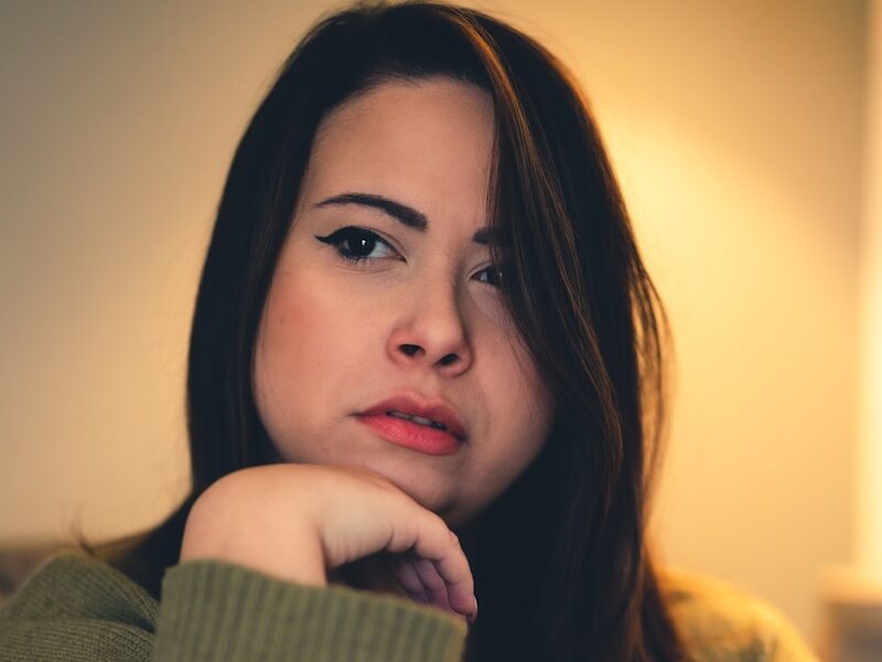a woman sitting on a couch with her hand on her chin