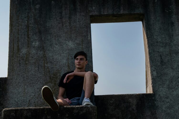 man in black tank top and blue denim jeans sitting on concrete bench