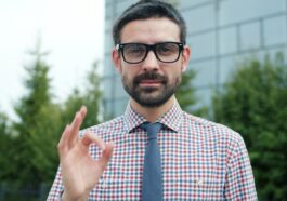 Man in glasses giving an okay sign.