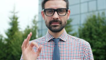Man in glasses giving an okay sign.