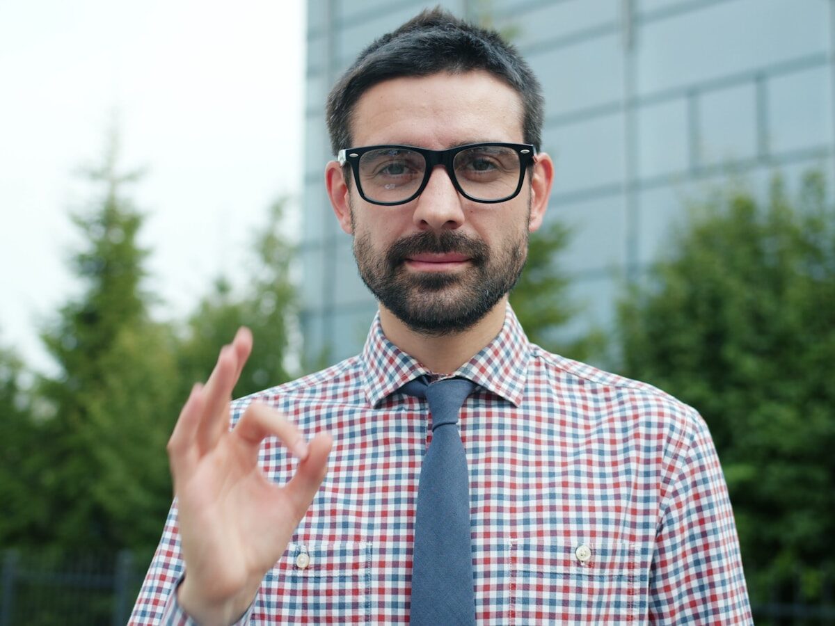 Man in glasses giving an okay sign.