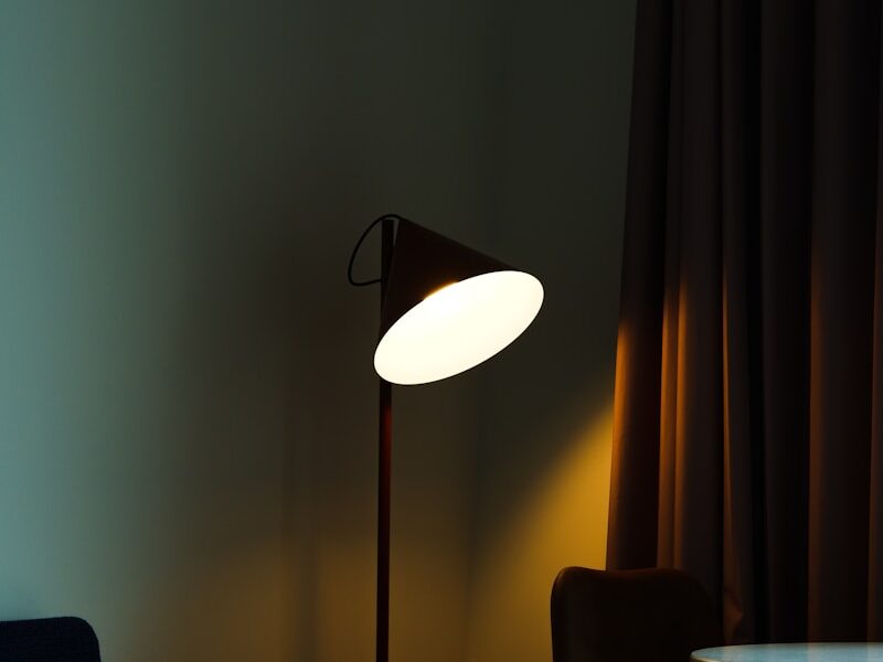 black and white torchiere lamp turned on near brown window curtain