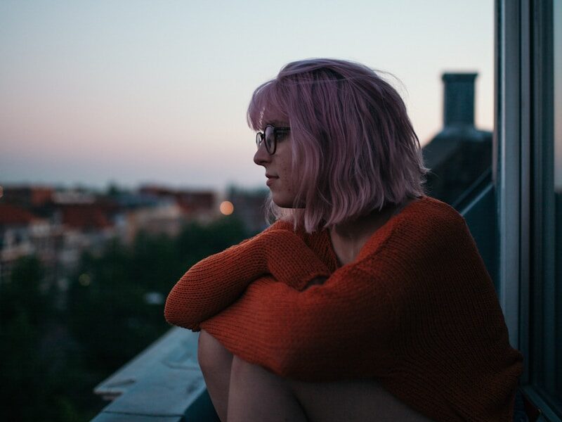 woman sitting near window near building