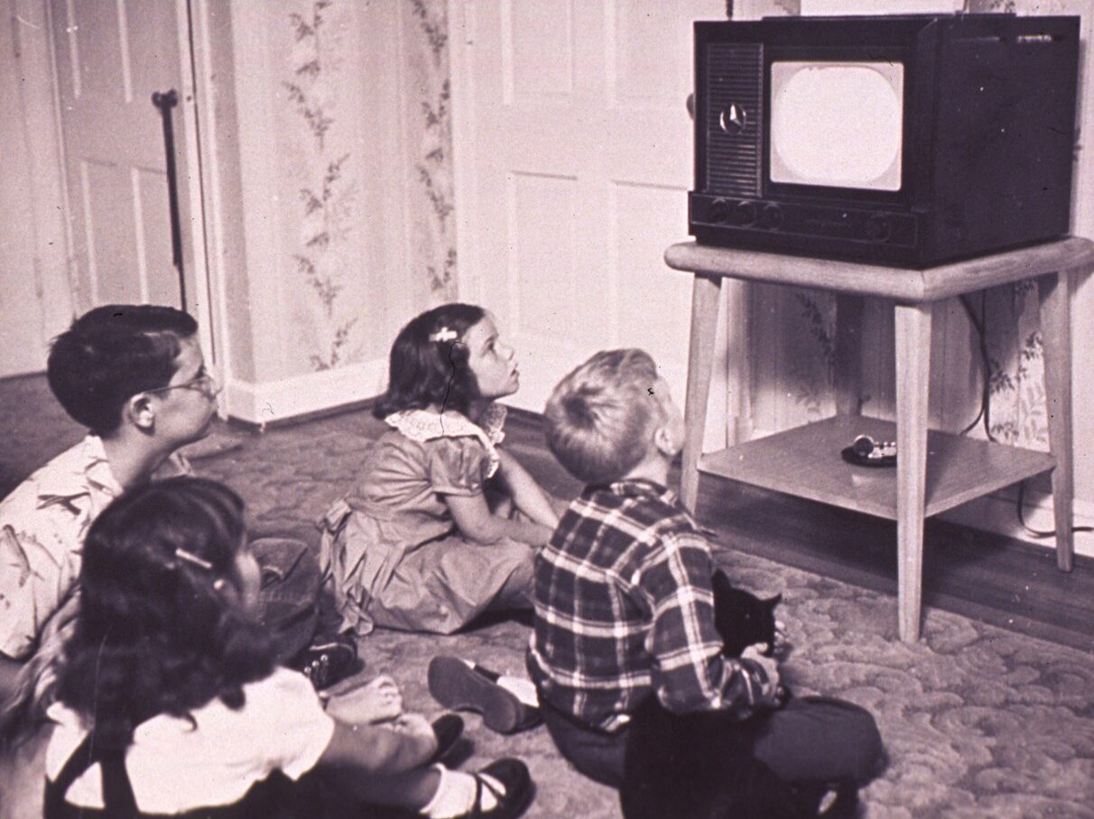 a group of children sitting on the floor in front of a tv