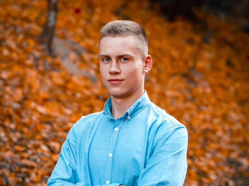 man in blue dress shirt standing on brown leaves during daytime