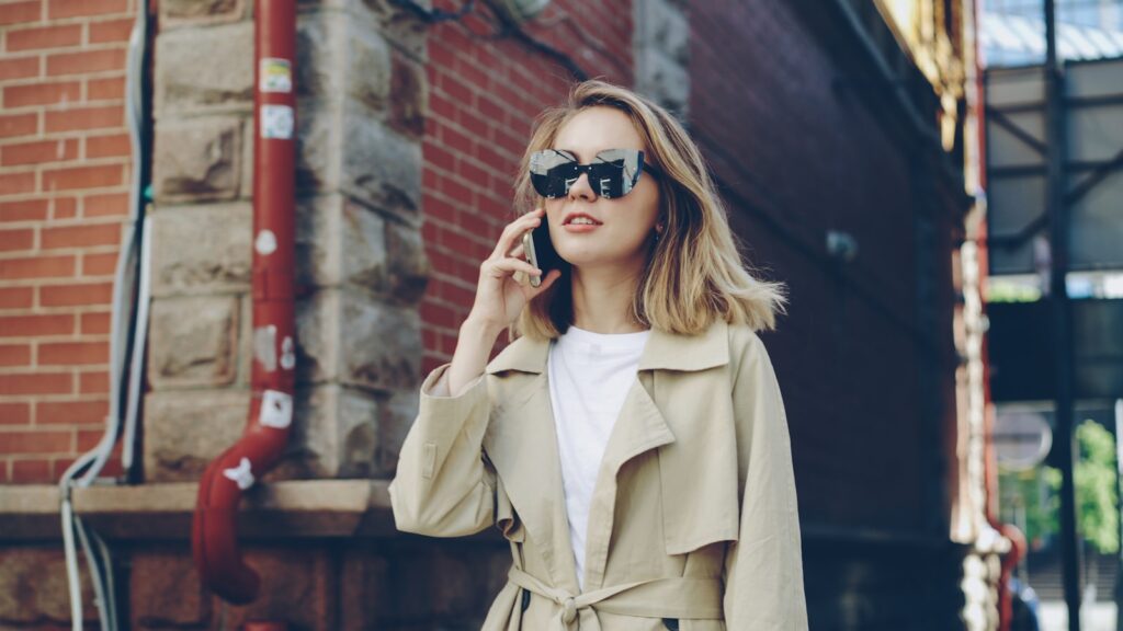 Woman in trench coat talking on phone outdoors
