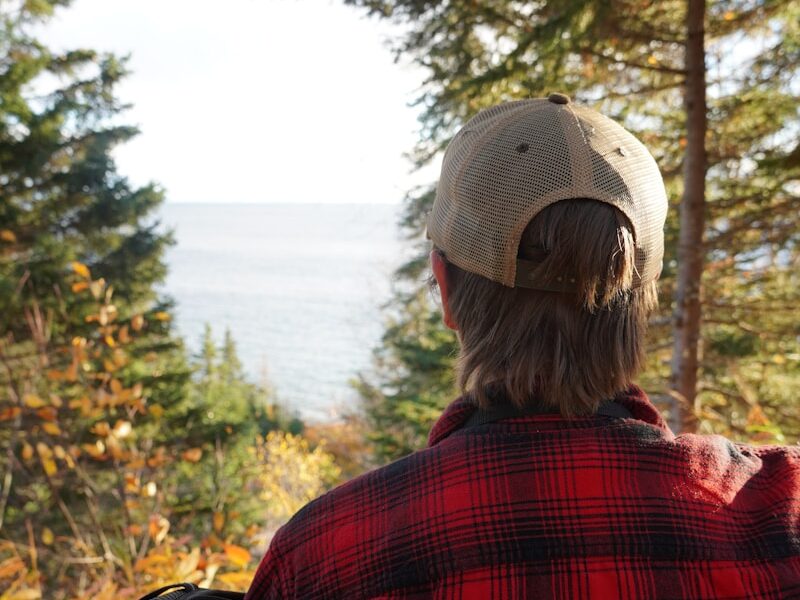 a person sitting on a ledge looking out at the water