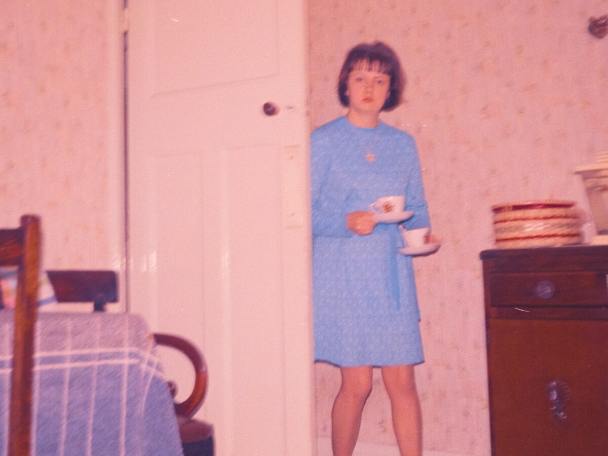 Woman in blue dress holding teacups in room