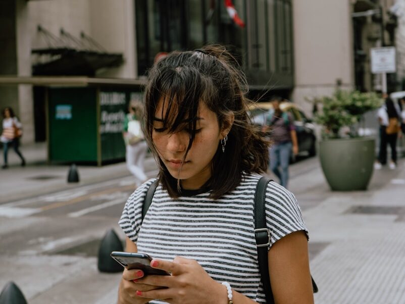 woman in black and white stripe shirt using smartphone