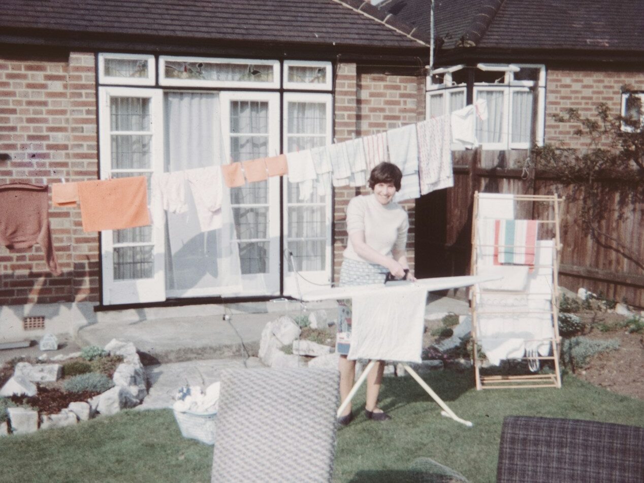 a woman standing in front of a house next to a lawn