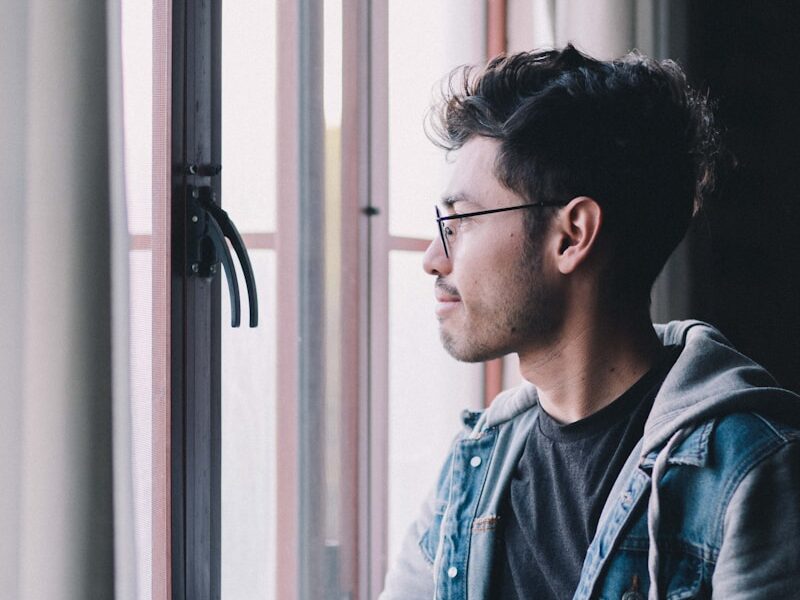 man in blue denim jacket wearing black framed eyeglasses