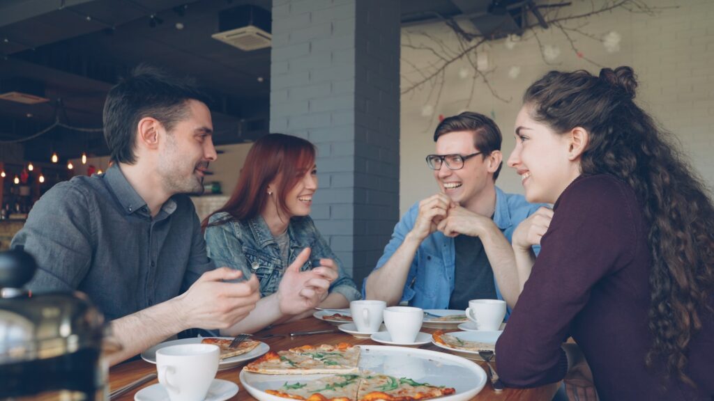 Friends enjoy pizza and conversation at a restaurant.