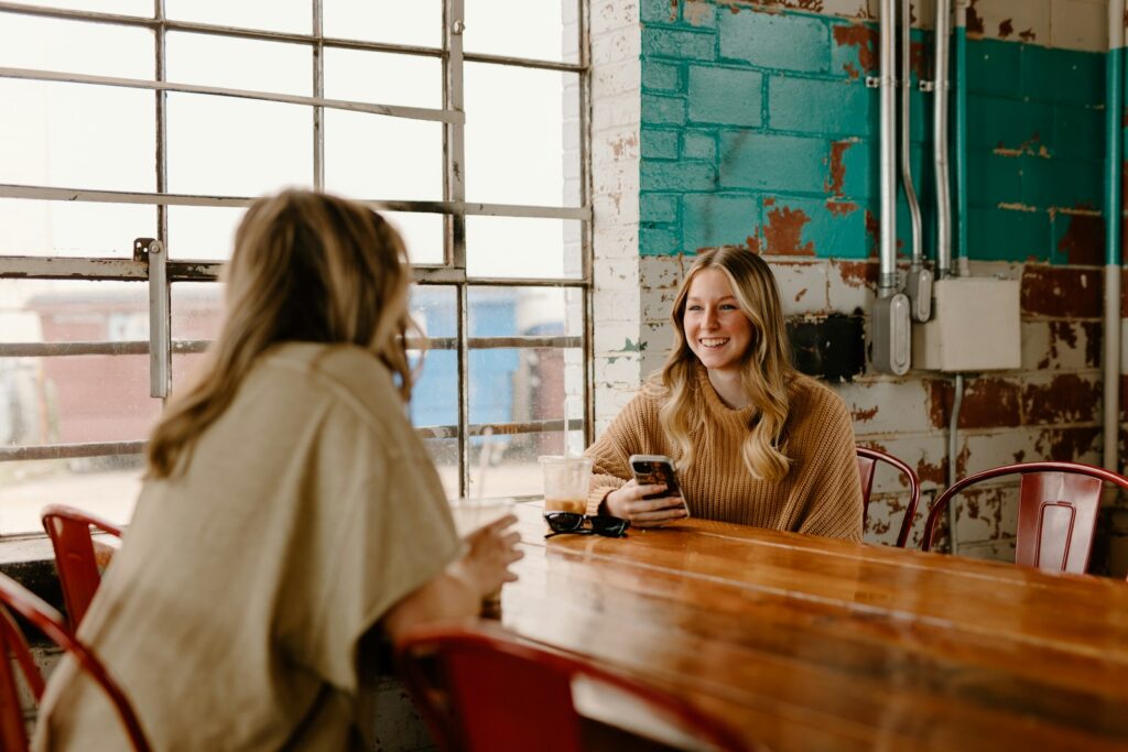 a woman sitting at a table with a cell phone