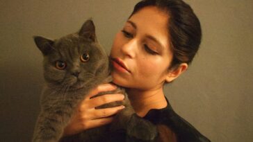 woman in black shirt holding gray cat