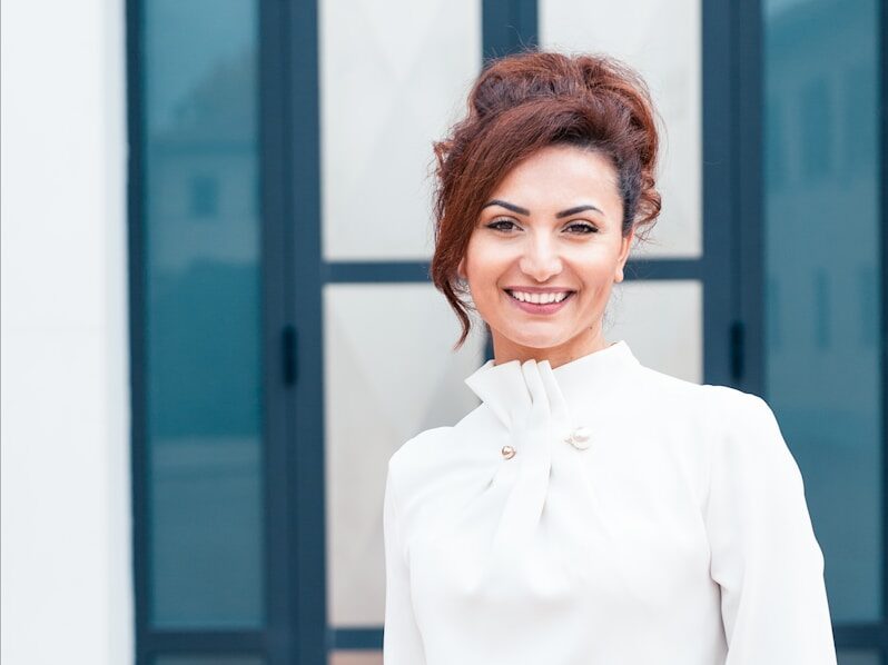 woman in white dress shirt and blue denim jeans smiling