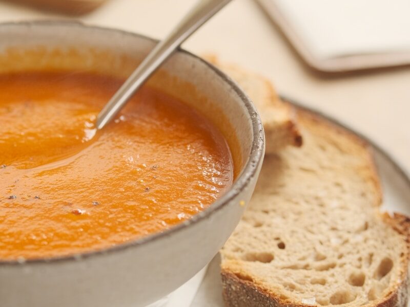 a bowl of soup and a piece of bread on a plate