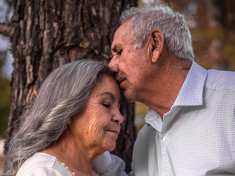 man in white button up shirt kissing woman in white sleeveless dress