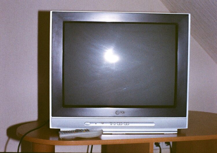 A television set with a remote control on a table.