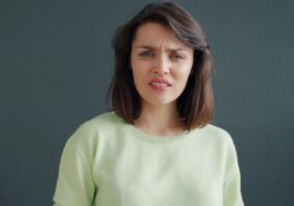 Woman with a disgusted expression against a dark background