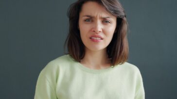 Woman with a disgusted expression against a dark background