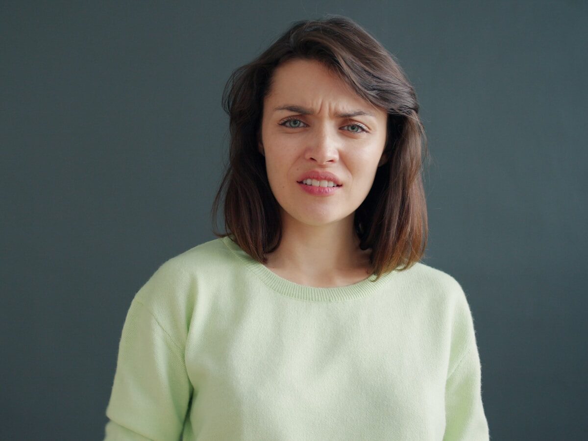 Woman with a disgusted expression against a dark background