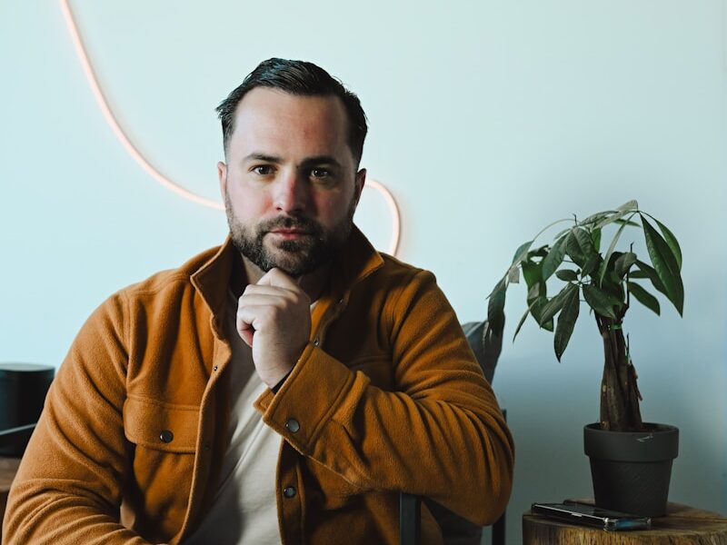 Man in a brown jacket sitting in a chair.