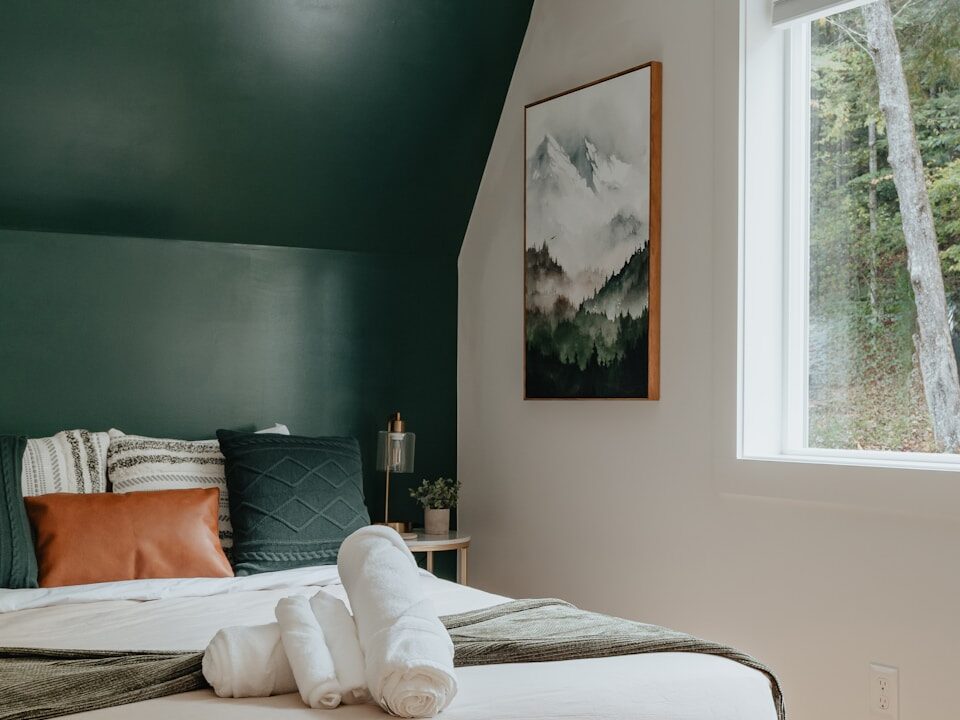 a bed with a white blanket and two folded towels on top of it