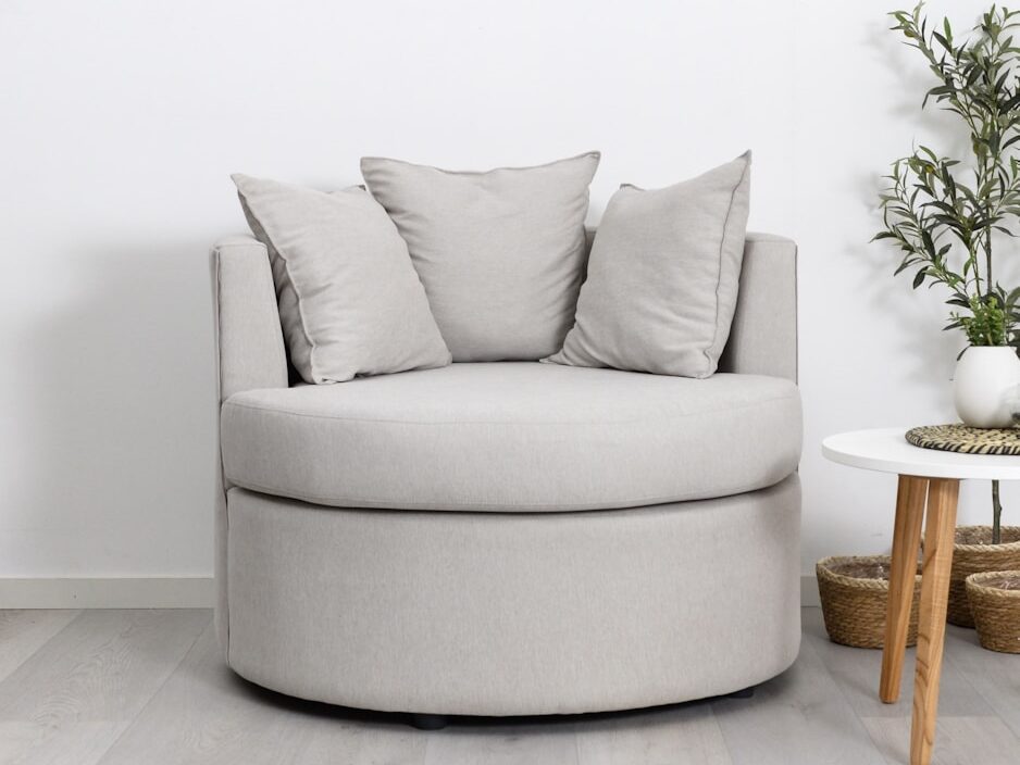 A round, light gray armchair with pillows.