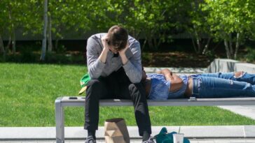 man sitting on white metal bench during daytime