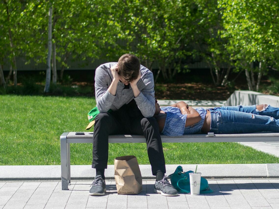 man sitting on white metal bench during daytime