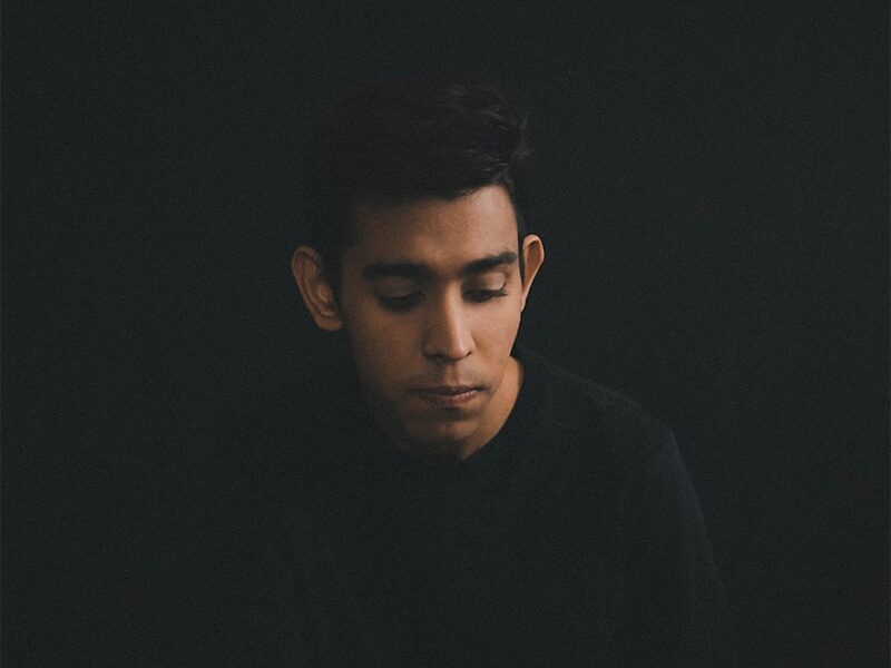 man wearing black long-sleeved shirt sitting while looking down