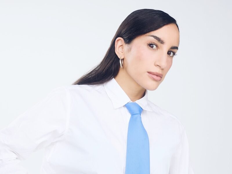 Woman in white shirt and blue tie with jewelry