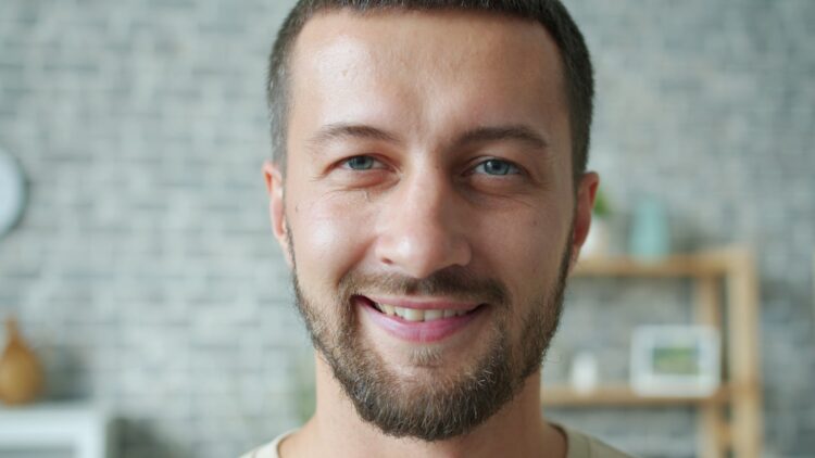 A smiling man with a beard and blue eyes.