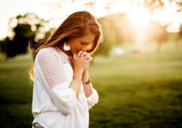 woman praying beside tree