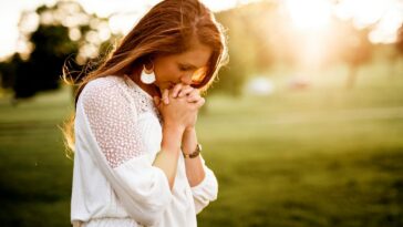 woman praying beside tree