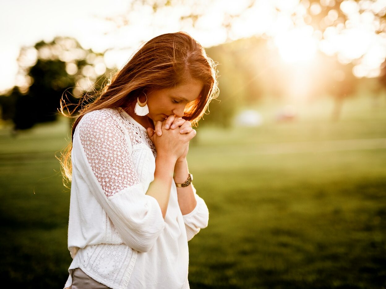 woman praying beside tree