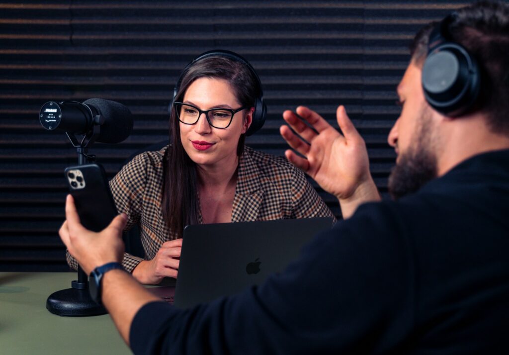 a man and woman with headsets on looking at a laptop