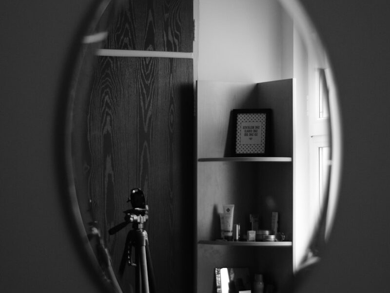grayscale photo of man standing in front of mirror