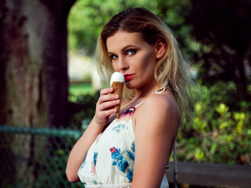woman in white and blue floral sleeveless dress sitting on brown wooden bench